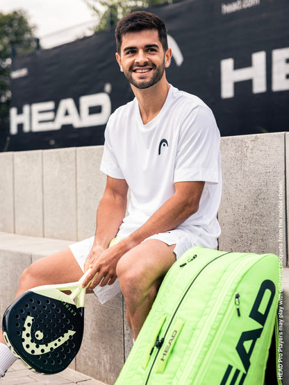 A smiling man in white sportswear sits on a concrete bench, holding the HEAD Extreme Pro 2026 Padel Racket, designed for advanced padel players. A neon green HEAD sports bag and a black HEAD banner are visible in the background.