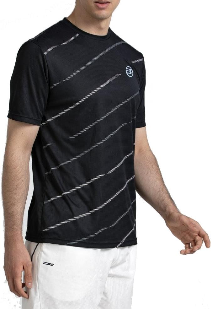 A man wearing the Bullpadel Casinas Mens Padel T-Shirt in black, made from lightweight polyester with Quickerdry technology, and white shorts stands against a plain white background.
