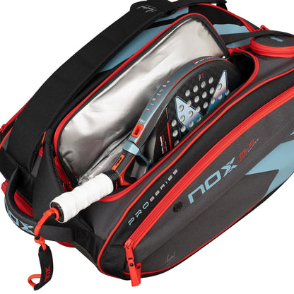 A NOX ML10 Competition XL Compact Padel Racket Bag in black and red is open to reveal a NOX padel racket with a white grip and blue-black face. The bag includes insulated lining and several compartments for storage.
