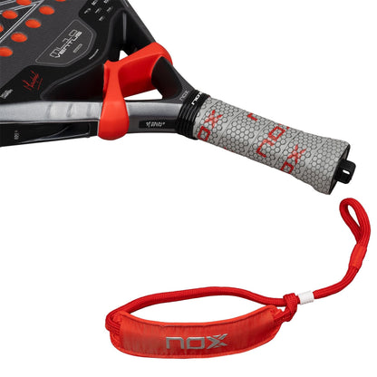 A close-up of the NOX ML10 Ventus Control 3K By Miguel Lamperti 2026 padel racket features a grey grip, red “NOX” logo pattern, red accent near the handle, and a detachable red NOX-labeled wrist strap below it.