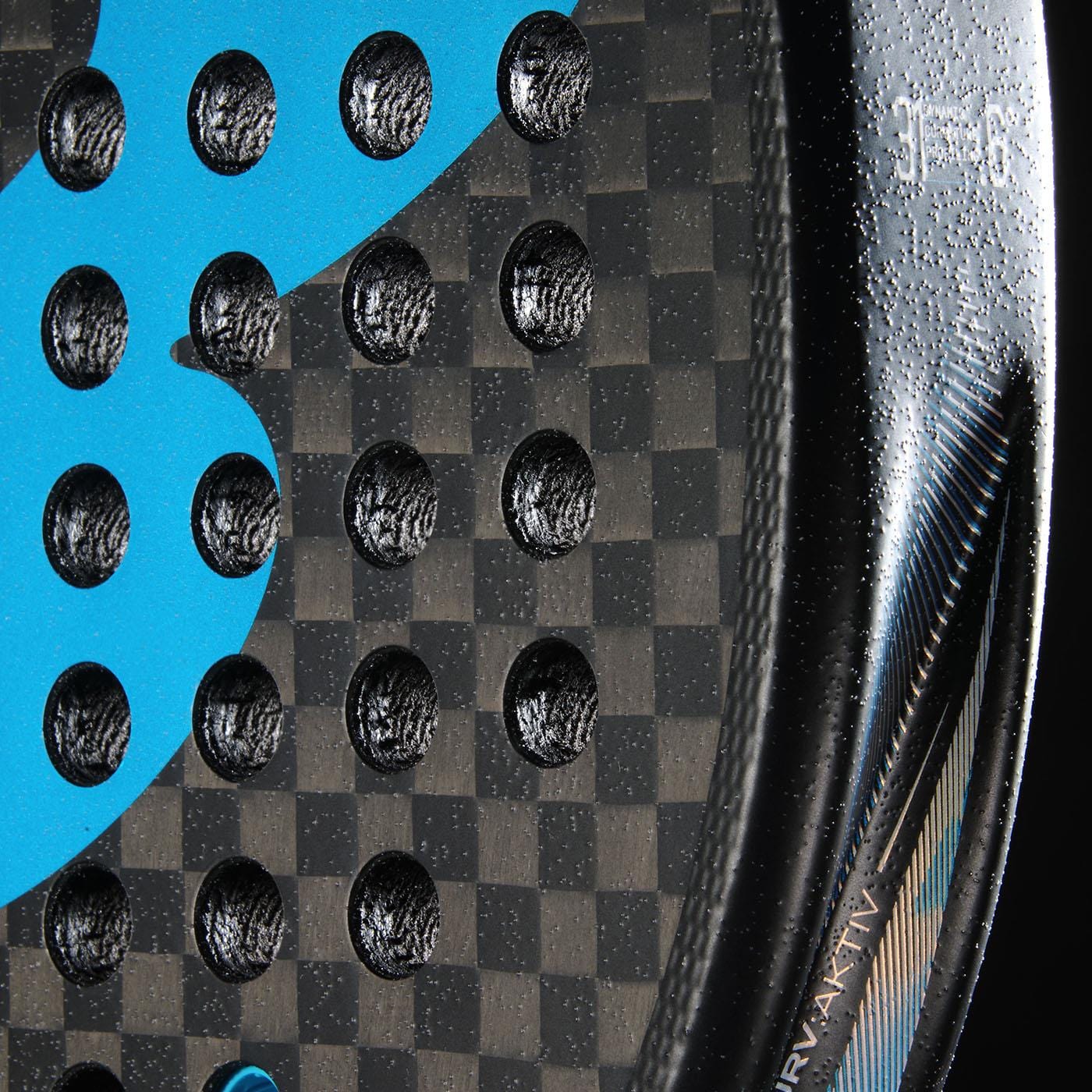 Close-up of the Bullpadel Vertex 05 Hybrid 2026 Padel Racket in black/blue, featuring a checkered carbon fiber pattern, round holes, blue graphic detail, textured surface, and part of a white printed label on its glossy edge.