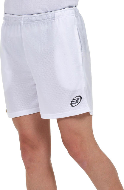 A person wears Bullpadel Campaza Mens Padel Shorts in white, featuring Quickerdry technology and an embroidered black and white logo on the left leg. Only the lower torso and upper legs are visible against a white background.