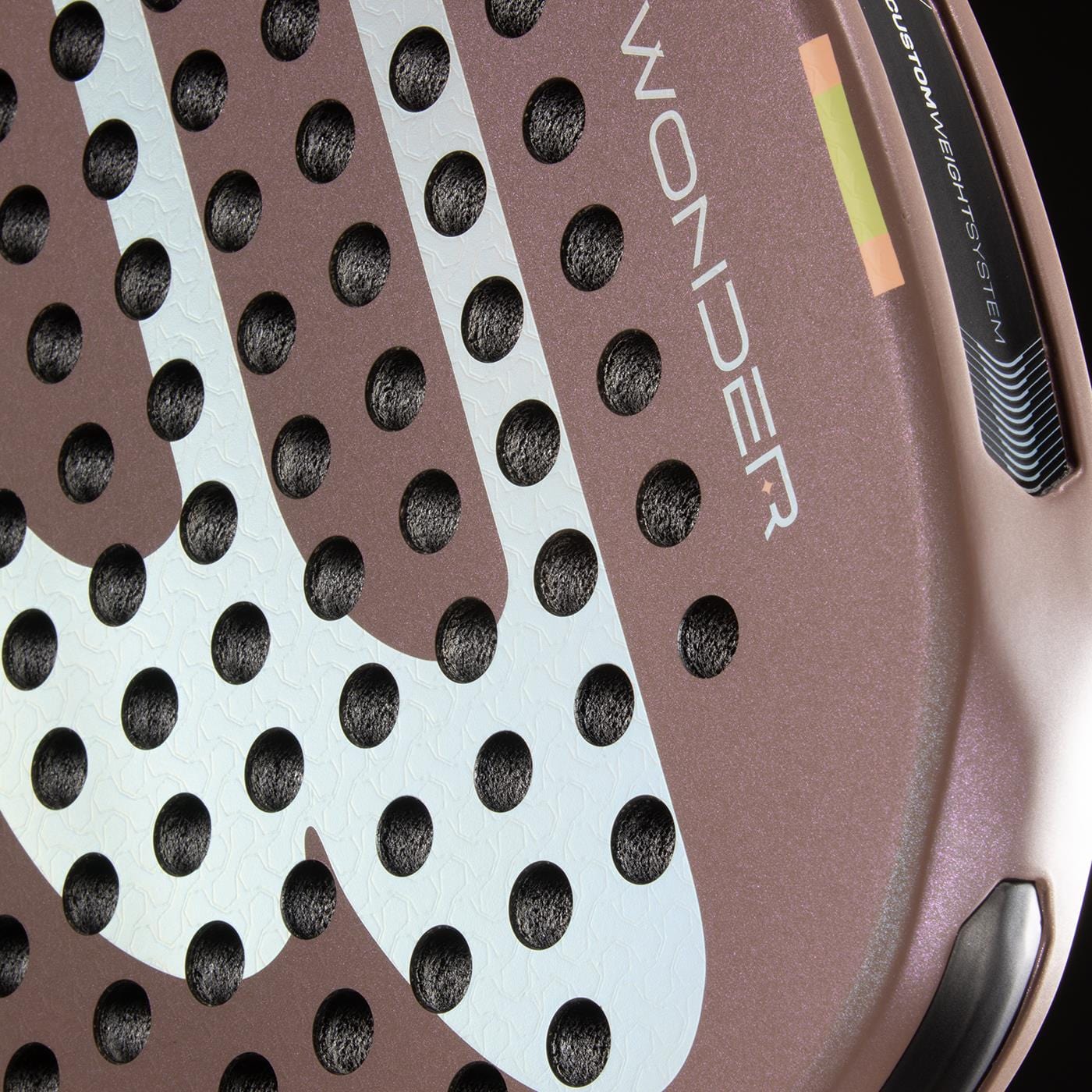 Close-up of the Bullpadel Wonder 2026 Padel Racket - Rose Gold by Bullpadel, featuring a textured rose gold surface, white graphics, circular holes, "WONDER" branding, part of the rim, and Hyper Core details.