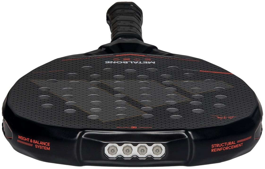 Close-up of the adidas Metalbone by Ale Galán 2026 Padel Racket - Black, showing its textured surface with circular holes and hexagonal pattern. "Weight & Balance System" and "Structural Reinforcement" are printed on its adjustable edge.