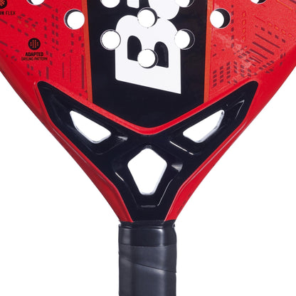 Close-up of the base of the Babolat Alioth Pro Junior Padel Racket in red and black, highlighting the black handle, white geometric cutouts, bold black and white "B" logo, and patterned design by Babolat.