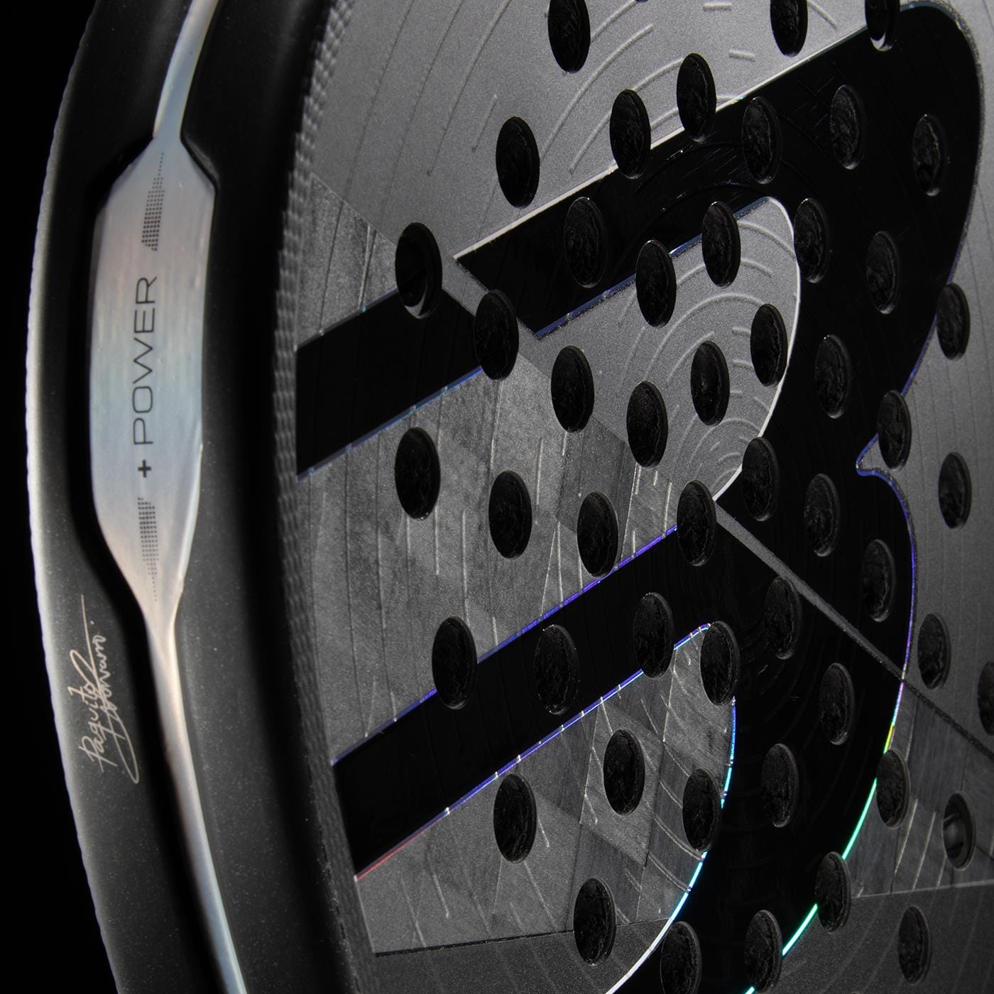 Close-up of the Bullpadel HACK 04 Hybrid 2026 Padel Racket in grey/black, featuring a textured surface, perforated holes, and a large stylized “S” logo with metallic edge engraved "POWER" and a signature, capturing its dynamic power.