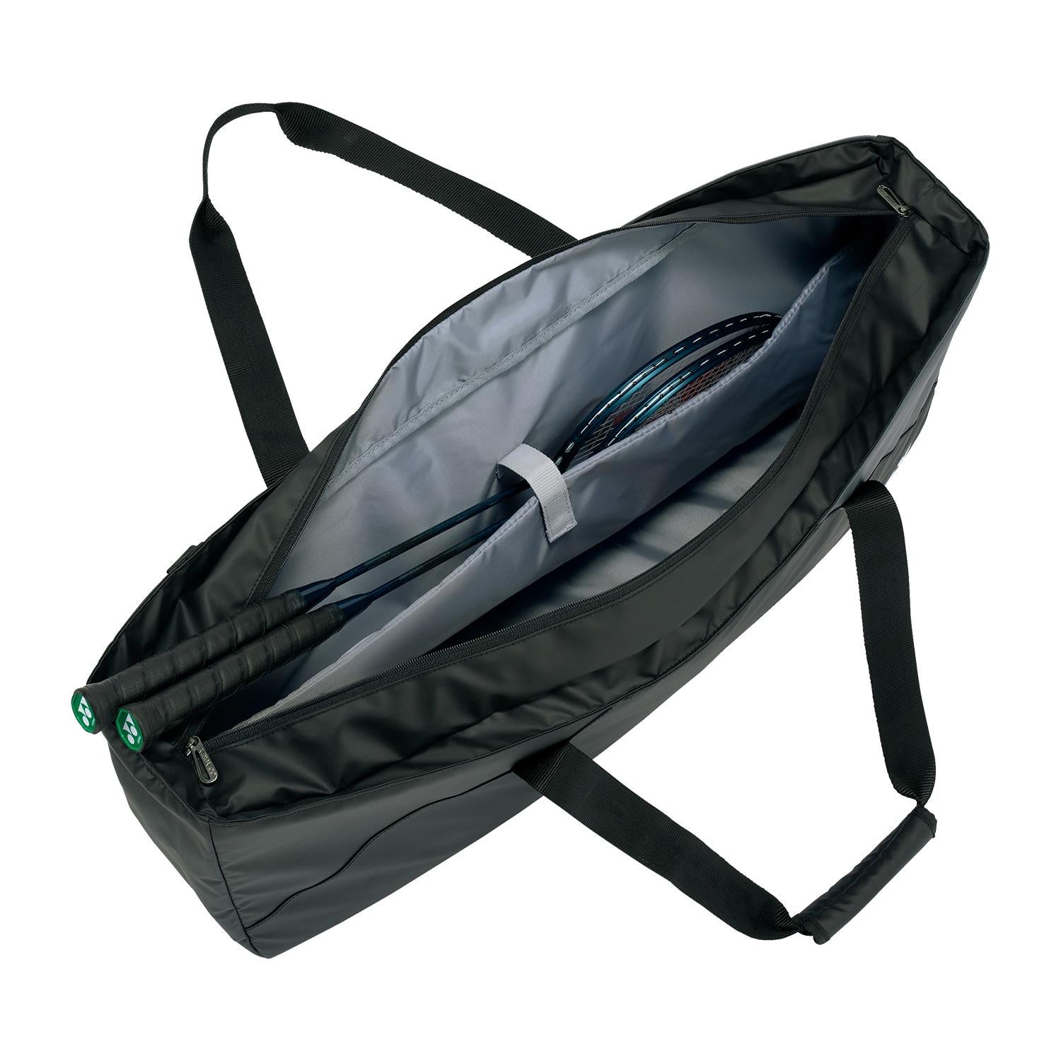 The Yonex 52531EX Club Tournament Padel Bag in grayish blue, featuring short handles and a shoulder strap, has a dedicated racket divider inside. Two badminton rackets are neatly placed within the partially open zipper revealing its gray interior lining.