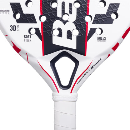 Close-up of a Babolat Technical Vertuo Juan Lebrón Padel Racket, displaying the brand name in bold. The racket has a geometric black and red design on white, with visible holes and a white grip handle, reflecting Juan Lebrón's style.