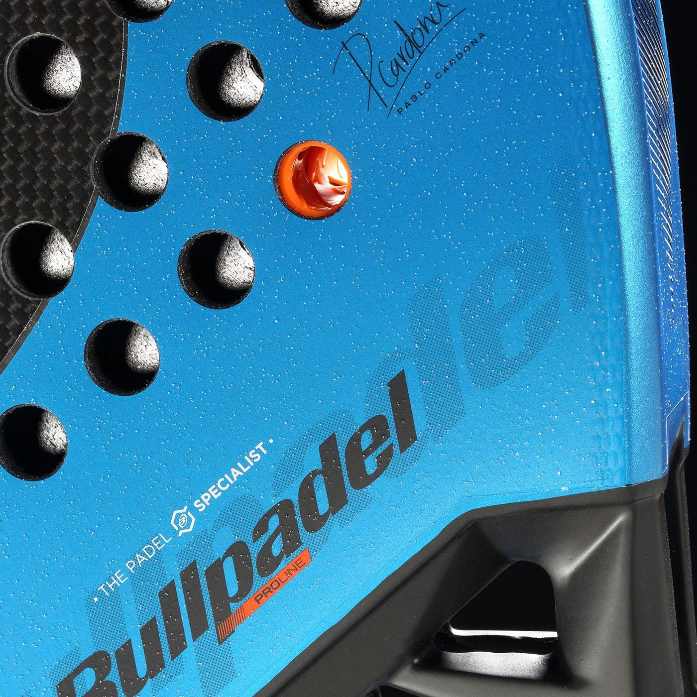 Close-up of the Bullpadel Vertex 05 GEO 2026 Padel Racket in blue and black, highlighting the Bullpadel brand name, textured black grip with raised bumps, orange detail, and signature from a top padel coach—a high-performance racket.
