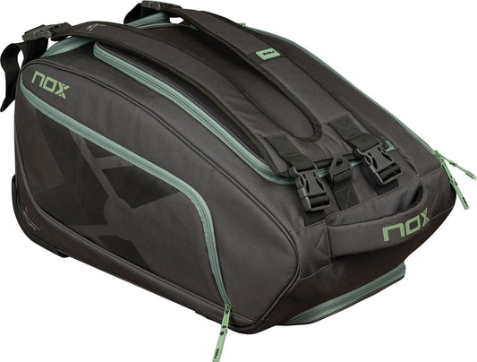 The NOX AT10 Competition Trolley Padel Bag in black and green features green zippers, shoulder straps, and multiple compartments, perfect for carrying rackets and sports equipment.
