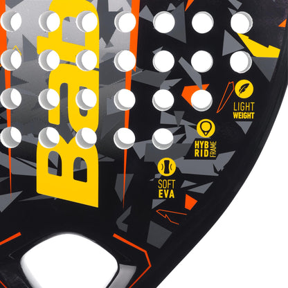 A close-up of the Babolat Storm Padel Racket - Black / Yellow, ideal for beginner to intermediate players, showcases its teardrop-shaped head with a striking geometric design in black, yellow, and orange. The bold yellow "Babolat" logo is accompanied by icons for "Soft EVA," "Hybrid Frame," and "Light Weight," with circular holes spread across the surface.