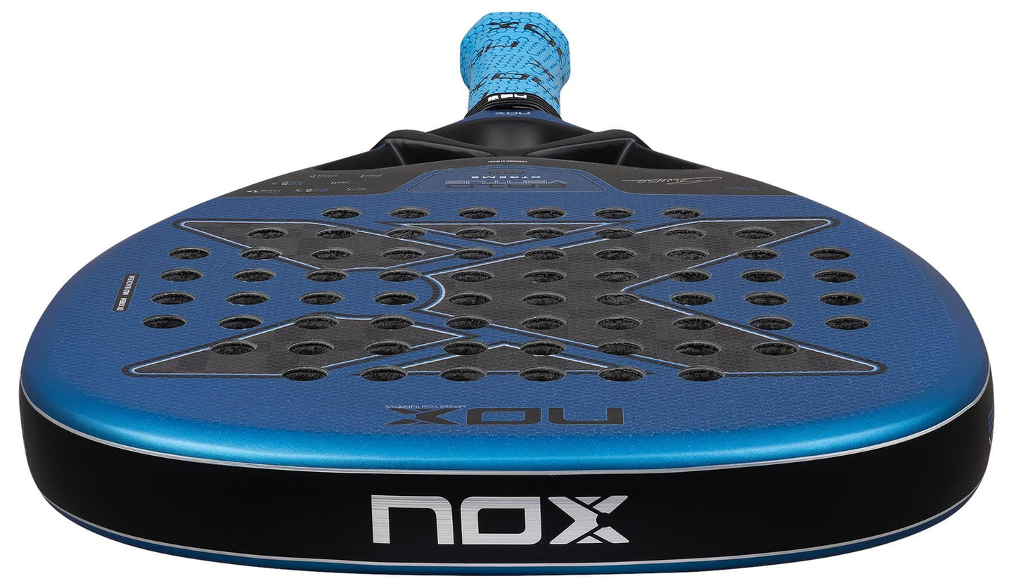 Close-up of the NOX Luxury EA10 Ventus Attack 12K XTREM By Edu Alonso 2026 Padel Racket in blue and black, showing its perforated 12K XTREM Carbon surface, textured grip handle, and prominent NOX branding on the face and edge.