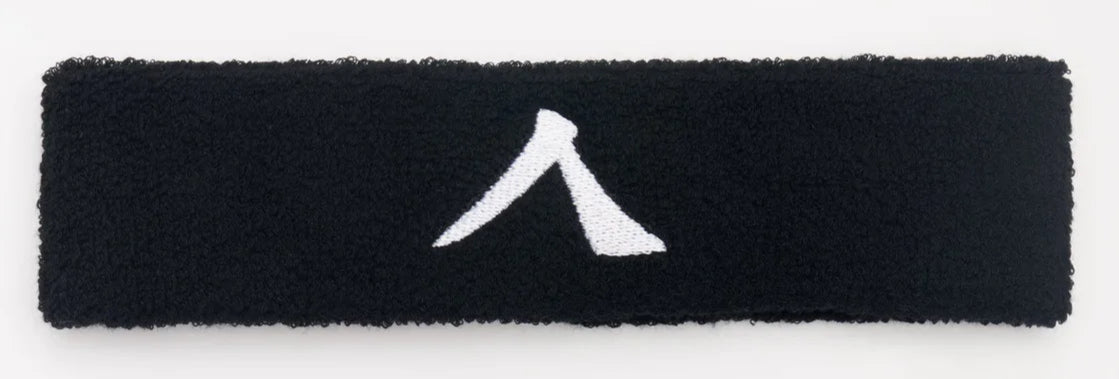 The Kanso 4cm Headband - Black, made by Kanso, features absorbent fabric for comfort and showcases a sleek design with a white triangular logo centered.