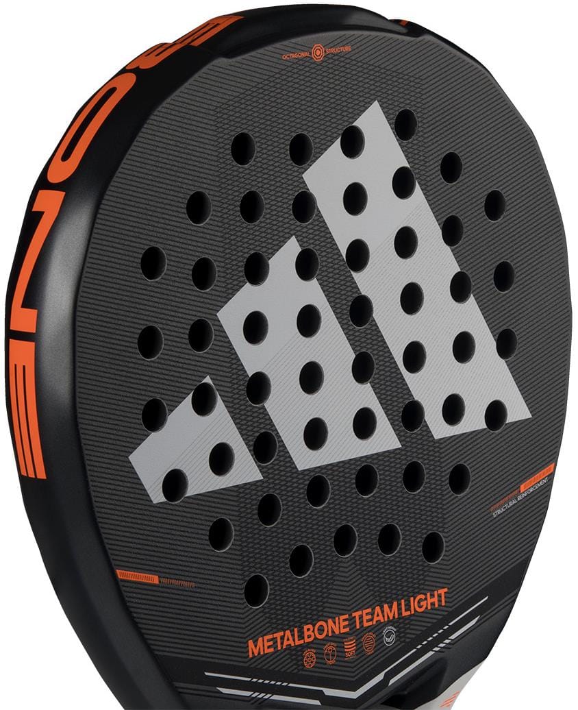 Close-up of the black adidas Metalbone Team Light 2026 padel racket, featuring orange details, a white adidas logo, multiple circular holes, and "METALBONE TEAM LIGHT" text near the bottom. Designed for advanced players.