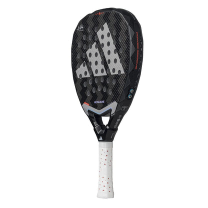 The ADIDAS Metalbone 3.4 Padel Racket in Black/White is ideal for advanced players. It features a textured surface with white circles, an angular head design, and prominently displays the logo on its face. The handle is wrapped in a white grip with red dots.