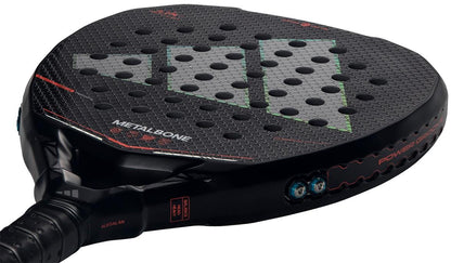 A close-up of the adidas Metalbone by Ale Galán 2026 Padel Racket - Black shows its hexagonal pattern, circular holes, green and red accents, Spin Blade Decal, "METALBONE" branding near the handle, and innovative adjustable weight system.