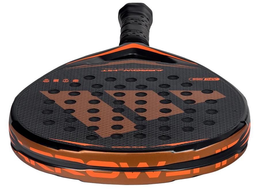A close-up of the adidas ADIDAS Arrow Hit Carbon CTRL 2026 Padel Racket, featuring a textured carbon fiber surface, perforated holes, and bold branding on the face, viewed from the handle.