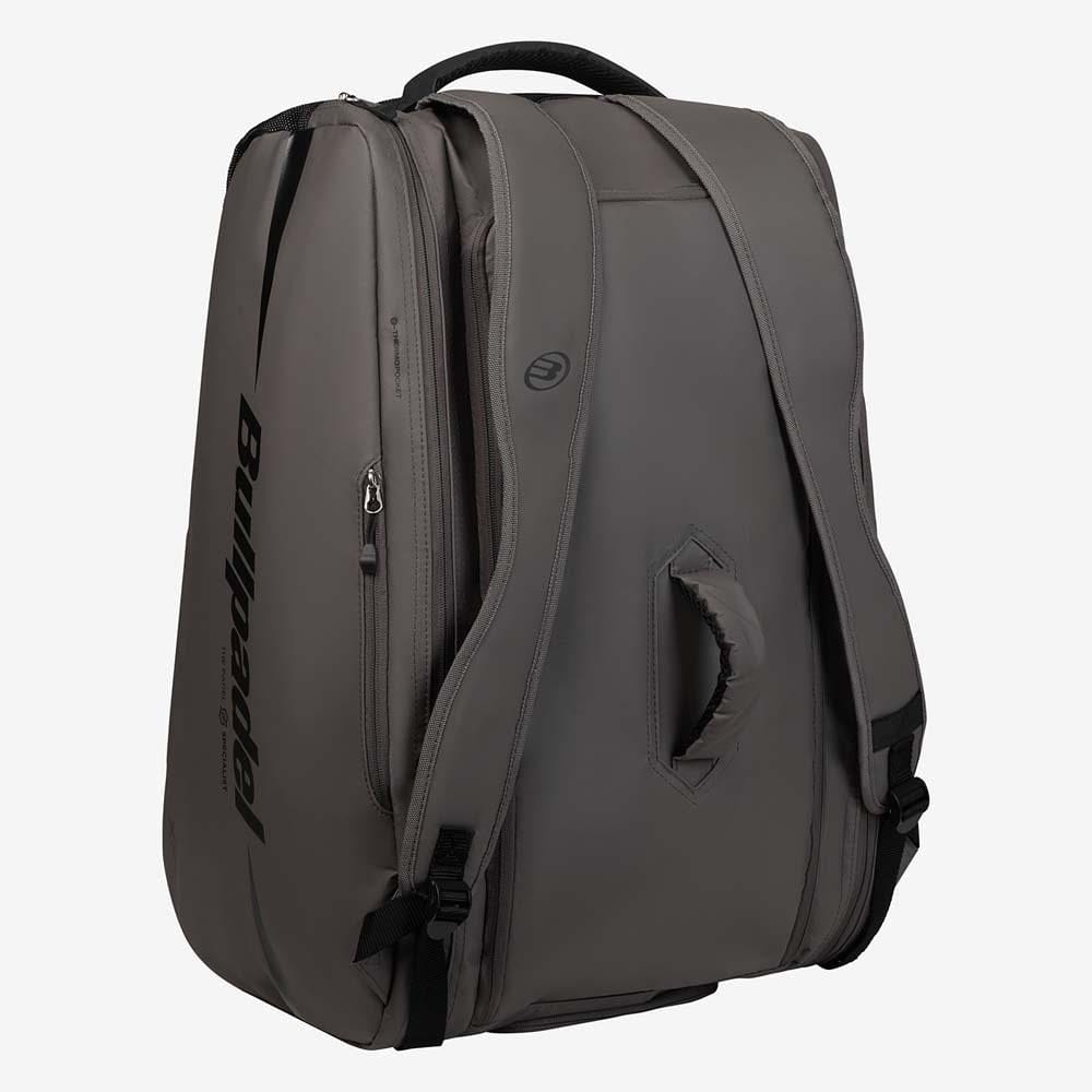 The Bullpadel BPP26022 XPLO Padel Racket Bag in grey features black straps, a padded handle, side zipper pocket, thermal racket compartments, and the Bullpadel logo on the side. The bag stands upright against a light background.