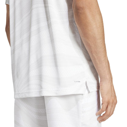 A person is wearing an ADIDAS Mens Club Graphic Padel T-Shirt in White/Grey, made from recycled materials. The back and arm of the shirt are shown, featuring subtle wave patterns, AEROREADY technology, and a small side slit near the hem.