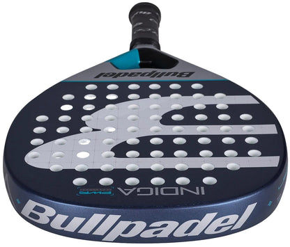 A close-up of the Bullpadel Indiga Pwr 2026 Padel Racket shows its dark blue surface with white holes and "Bullpadel" and "INDIGA" branding on the face and edge.