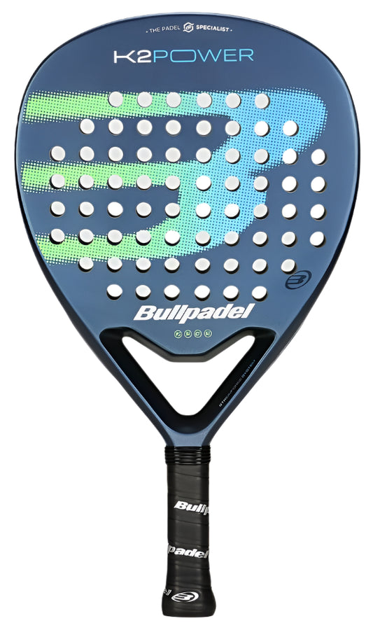 The Bullpadel K2 Power 2025 Padel Racket in blue features circular holes and green accents. "K2 Power" is displayed at the top, with "Bullpadel" near the handle. It has a teardrop shape and cushioned grip for enhanced performance.