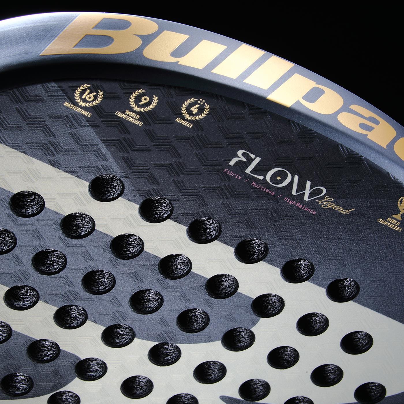 Close-up of the Bullpadel Flow Legend 2026 Padel Racket - Black, featuring its textured, perforated surface, gold Bullpadel branding, and award symbols on a dark background. Inspired by Alejandra Salazar’s championship legacy.