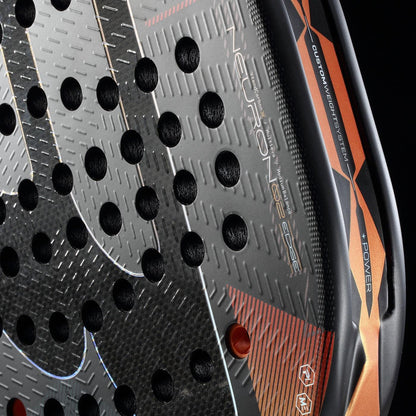 Close-up view of the Bullpadel Neuron 02 Edge 2026 Padel Racket in Black/Red, showing circular holes, textured surface, "NEURON 02 360g" and "CUSTOM WEIGHT SYSTEM" on the side, plus advanced PrismLock technology.