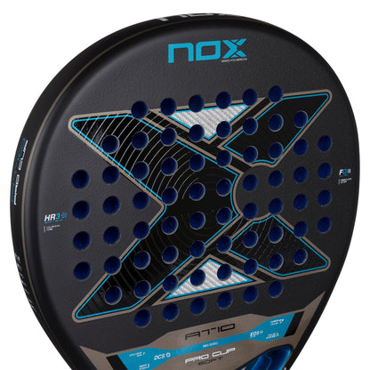 Close-up of the NOX AT10 Pro Cup Soft By Agustín Tapia 2026 Padel Racket, a black NOX racket with a blue "X" design, circular holes, and HR3 and Pro Cup Sport details on the edge. Inspired by Agustín Tapia.