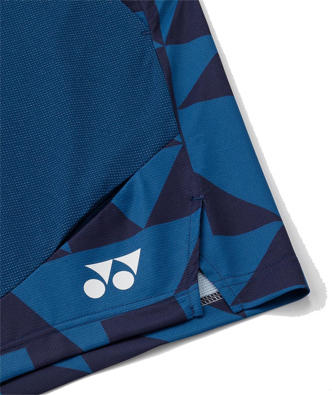 Close-up of a blue sports shirt's hem with a geometric pattern and white Yonex logo, matching Yonex 15240YX Knit Mens Padel Shorts - Indigo Blue by Yonex, made from breathable knit fabric for ultimate comfort.