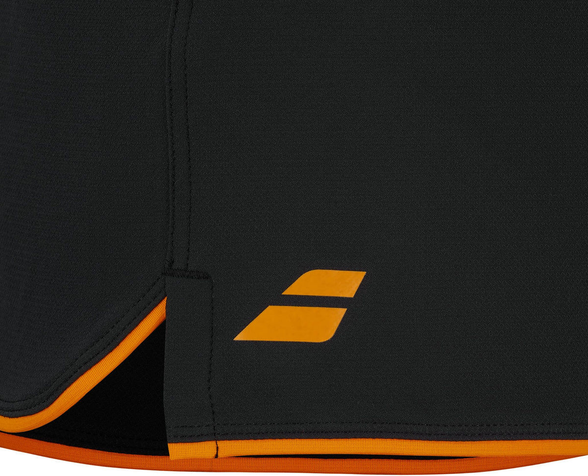 Close-up of a black fabric with yellow-orange trim and a small yellow-orange geometric logo near the corner, showcasing the premium detailing of the Babolat Perf Mens Padel Shorts – Black by Babolat. Ideal for men’s sports shorts enthusiasts who prioritize both style and performance on the court.