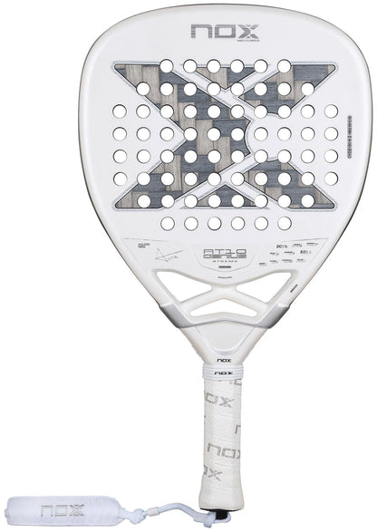 The NOX AT10 Genius Attack 12K Alum Extrem By Agustín Tapia 2026 padel racket features a bold X design, circular holes, and a comfortable wrapped grip with branded wrist strap—ideal for powerful play on the court.