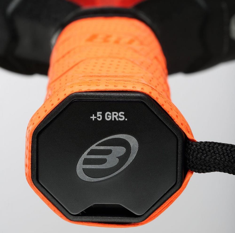 Close-up of a Bullpadel Custom Weight Padel Grip Plate with a bright orange textured grip. The black end cap features "+5 GRS." and the Bullpadel “B” logo, letting players fine-tune racket balance. A black strap is attached to the handle.