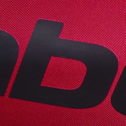 Close-up of a black letter "b" printed on textured burgundy fabric, likely part of the Babolat logo, as seen on the Babolat Court S Padel Racket Bag - Burgundy.