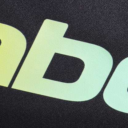 Close-up of lowercase yellow-green gradient letters "ab" on textured black evokes the modern, bold style of the Babolat Court S Padel Racket Bag - Black / Multi by Babolat, made from recycled polyester.