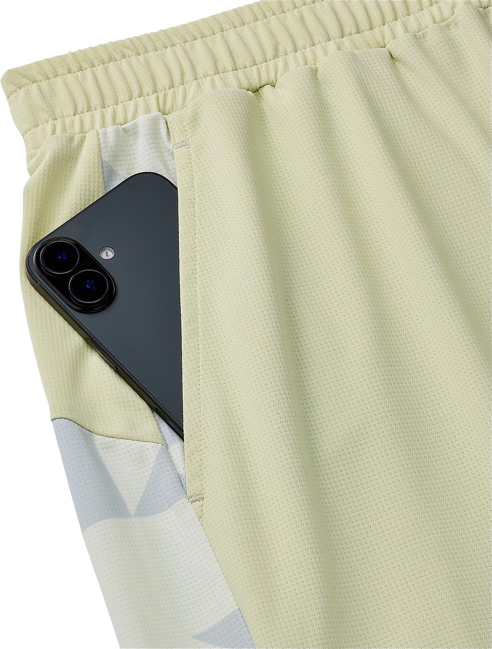 A black smartphone peeks out from the pocket of Yonex 15240YX Knit Mens Padel Shorts in Champagne, featuring a breathable knit fabric and elastic waistband.