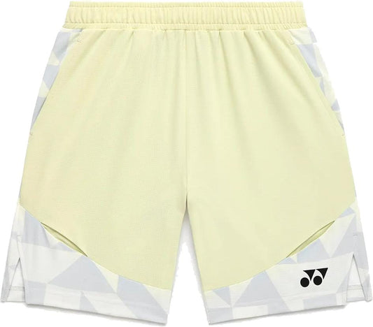The Yonex 15240YX Knit Men's Padel Shorts in Champagne feature light yellow breathable fabric, an elastic waistband, side pockets, geometric white and gray lower patterns, and a black logo on the right leg—perfect for padel.