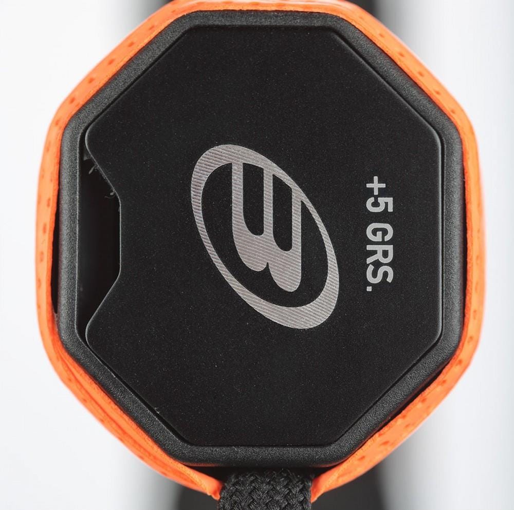 Close-up of a Bullpadel Custom Weight Padel Grip Plate, black and octagonal with an orange border, stylized "B" logo, "+5 GRS" text, and attached black braided cord to enhance racket balance and grip. Brand: Bullpadel.