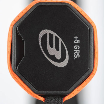 Close-up of a Bullpadel Custom Weight Padel Grip Plate, black and octagonal with an orange border, stylized "B" logo, "+5 GRS" text, and attached black braided cord to enhance racket balance and grip. Brand: Bullpadel.
