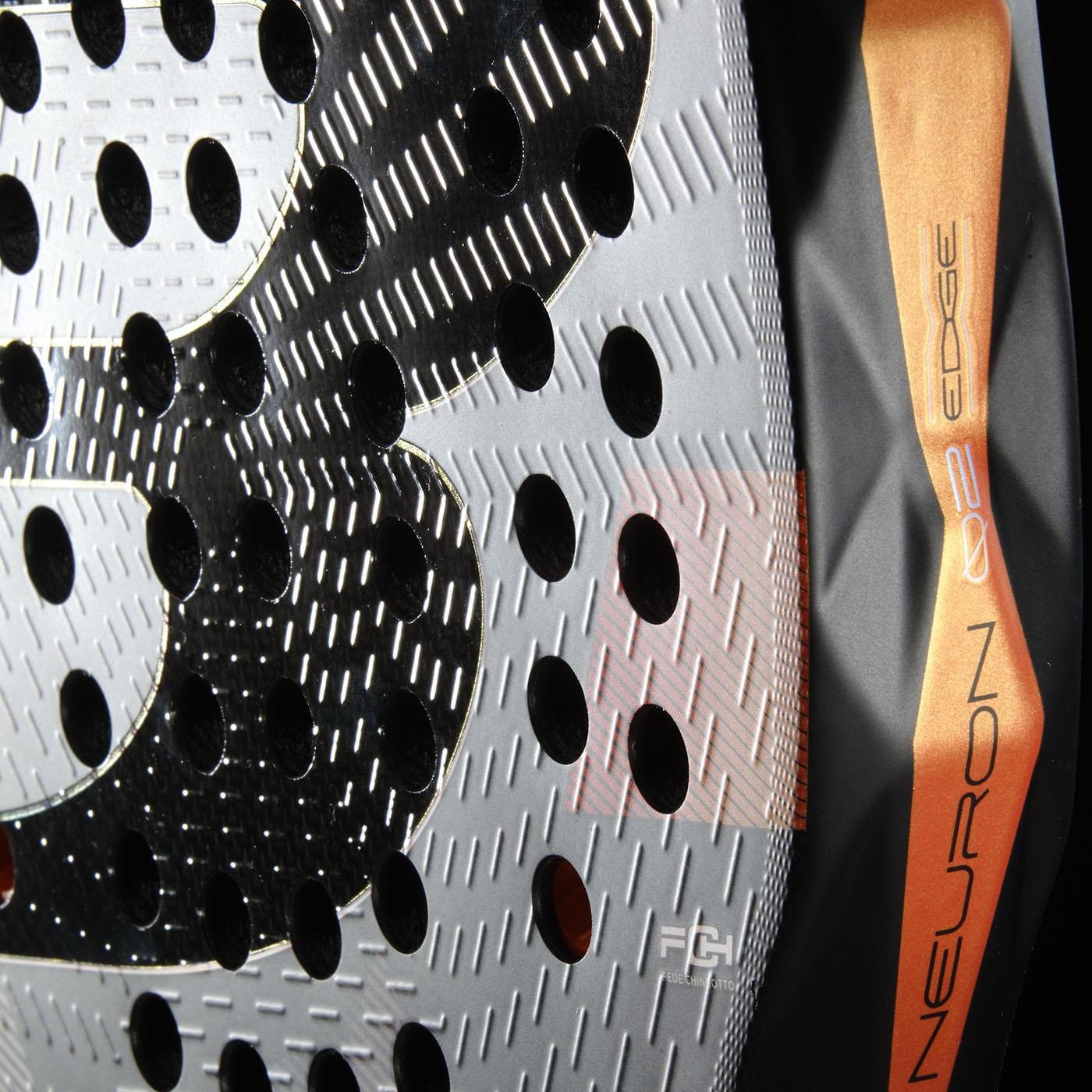 Close-up of the Bullpadel Neuron 02 Edge 2026 Padel Racket in black/red, featuring circular holes, a textured surface, and orange edge stripe with "NEURON O2 EDGE," emphasizing Bullpadel's advanced PrismLock technology.