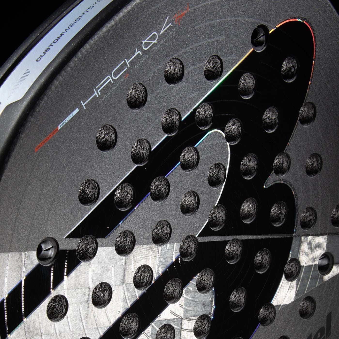 Close-up of the Bullpadel HACK 04 Hybrid 2026 Padel Racket in grey/black, featuring textured holes, a glossy finish, "HACK 04," "custom weight system," and the Bullpadel logo—designed for dynamic power.
