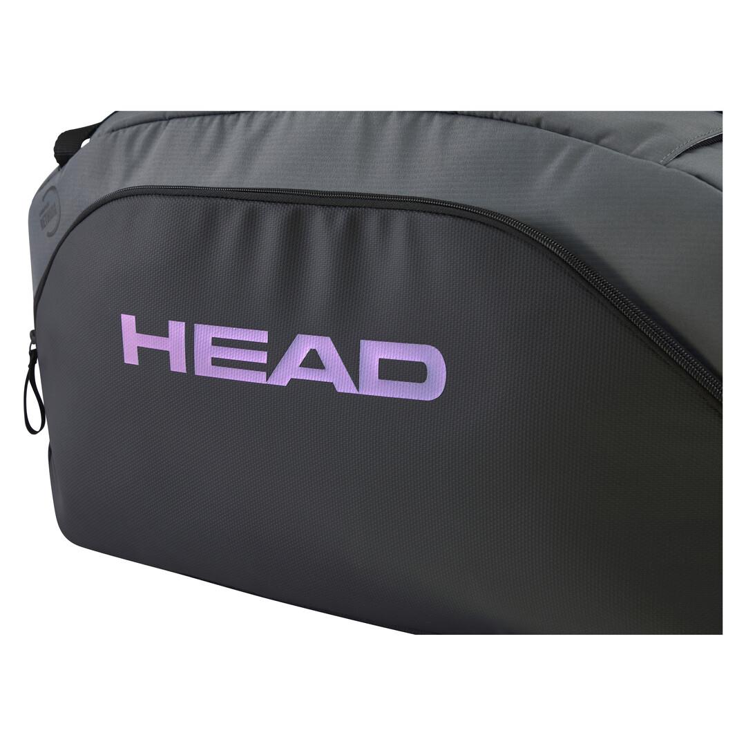 A close-up of the HEAD Pro X Duffle Padel Bag L in Black/Dark Grey, made from recycled PET bottles, with "HEAD" prominently displayed in large purple letters. It features a zippered compartment seamlessly integrated into its sleek design.