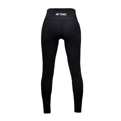 The Yonex YL2024 Women's Padel Leggings in black, set against a white background, feature a high waistband and moisture-wicking technology. The Yonex logo is prominently displayed on the waistband.