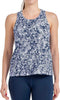A woman models the Bullpadel Pilme Women's Padel Tank Top in Deep Ocean—sleeveless, blue and white patterned—paired with navy leggings. Her face is not shown. Breathable performance sportswear by Bullpadel.