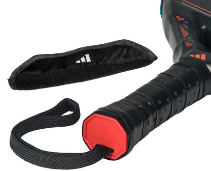 Close-up of the adidas Metalbone HRD+ by Ale Galán 2026 Padel Racket handle in black/red, featuring a wrist strap, beside a black velcro strap with logo for added grip or protection.