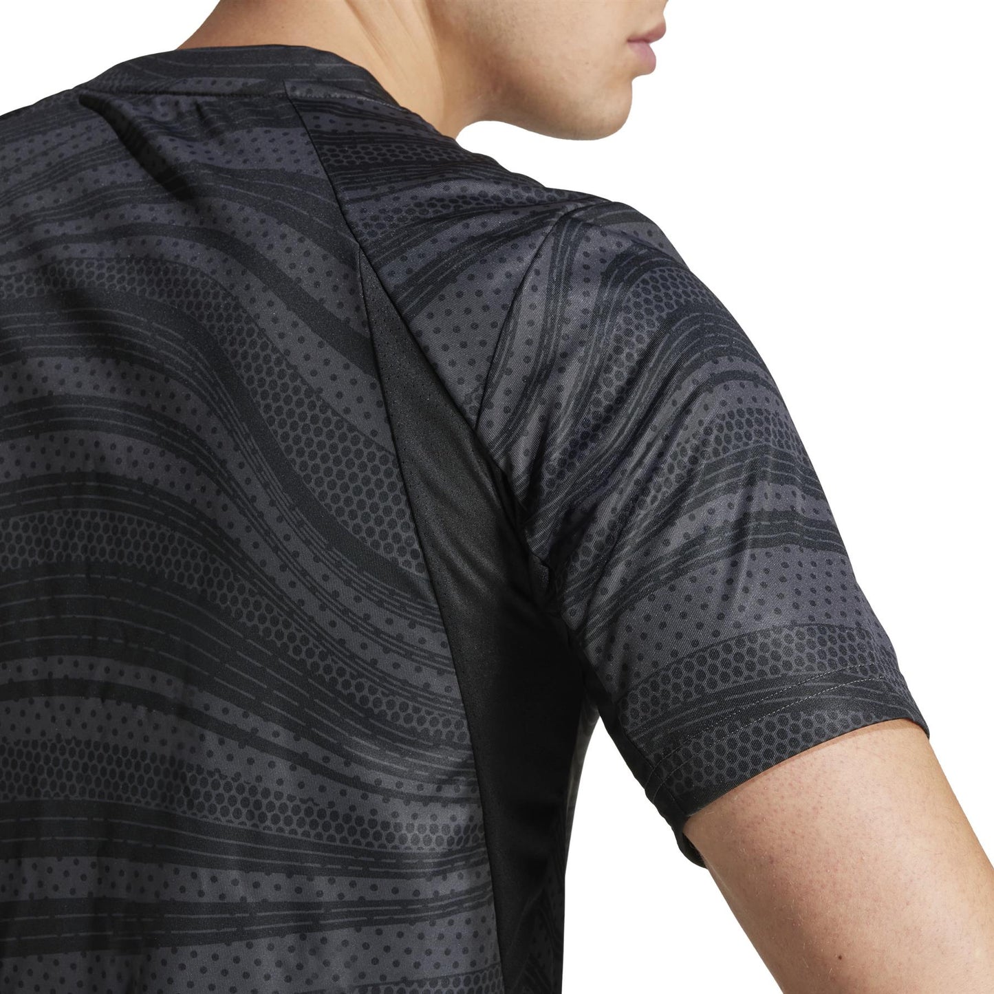 The ADIDAS Men's Club Graphic Padel T-Shirt showcases a back view from shoulders to mid-back, featuring black and gray wavy lines and dots on a white background. This athletic shirt by adidas is crafted from recycled materials.