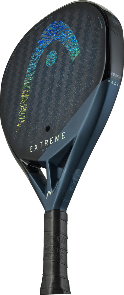 A close-up of the HEAD Extreme One 2025 Padel Racket by HEAD, featuring a black and blue frame, 12K Carbon Fibre texture, vibrant Head logo on the face, and black grip tape on the handle for comfort and control.