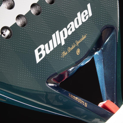 Close-up of the Bullpadel Icon 2026 Padel Racket - Green, featuring the Bullpadel logo, "The Padel Specialist" slogan, and a portion of its surface with a distinctive green frame and red detail.