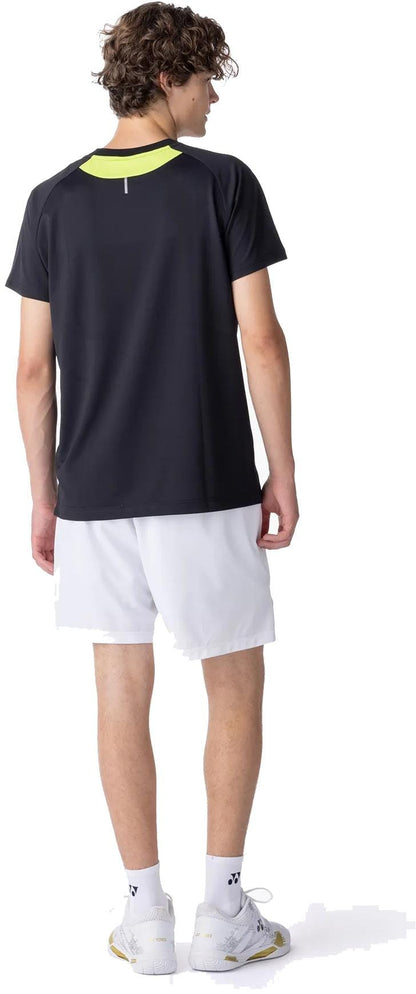 A young man with curly hair, facing away, wears the Yonex 10711YX Crew Neck Men's Padel T-Shirt in black, paired with white shorts, socks, and athletic shoes. He looks to his right against a white background.