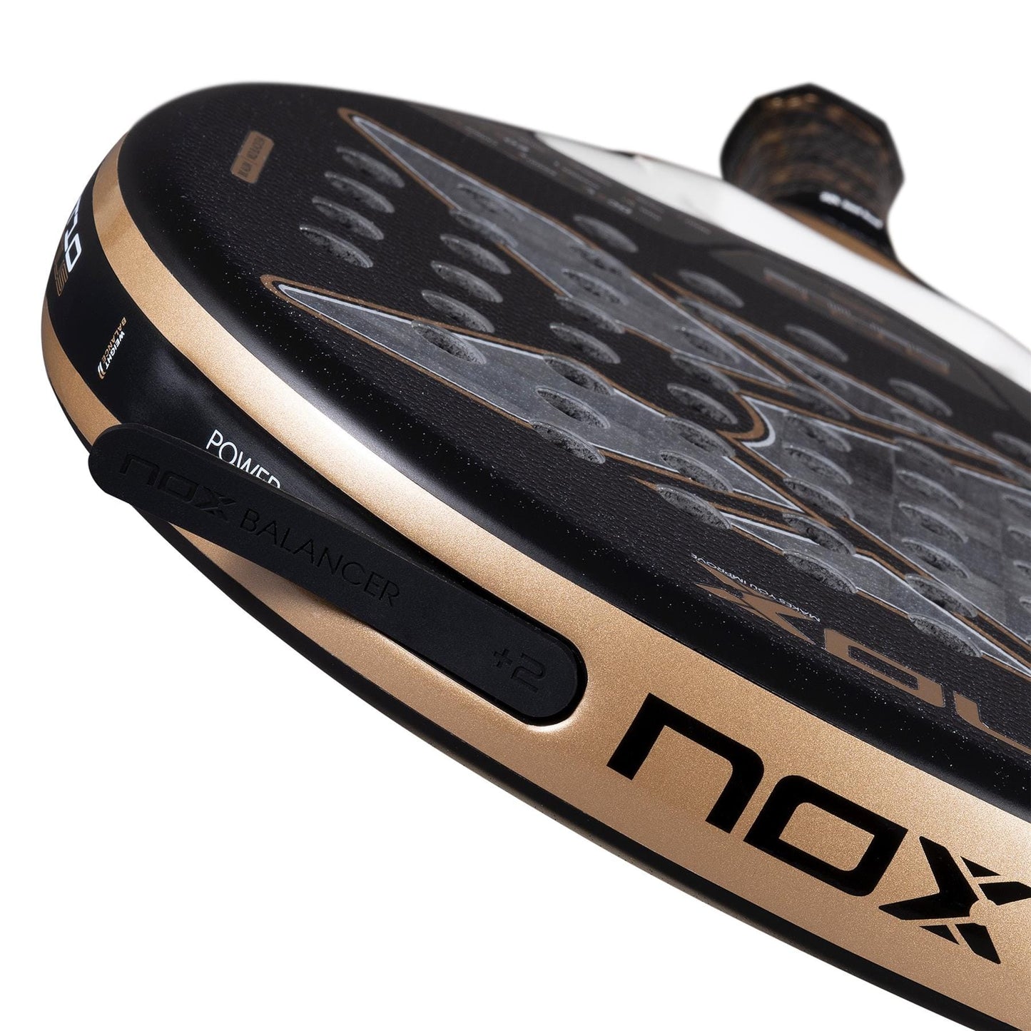 Close-up of the NOX AT10 Genius 18K Alum By Agustín Tapia 2026 Padel Racket in black and gold, with a perforated Dual Spin surface, “NOX BALANCER +2” on the edge, and a textured grip handle.