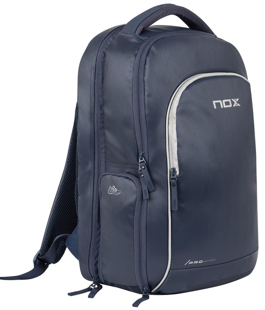 The NOX Pro Series Padel Backpack - Blue by NOX features multiple zippered compartments, padded straps, an air ventilation system, and a white logo on the front pocket. It is shown against a white background.